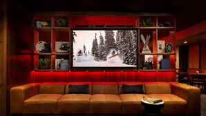 A cozy living room with a leather sofa, a flat-screen TV, and a red-lit entertainment unit. - Mt. Crested Butte Views + Restaurant. Pool. Spa. (Mt. Crested Butte)