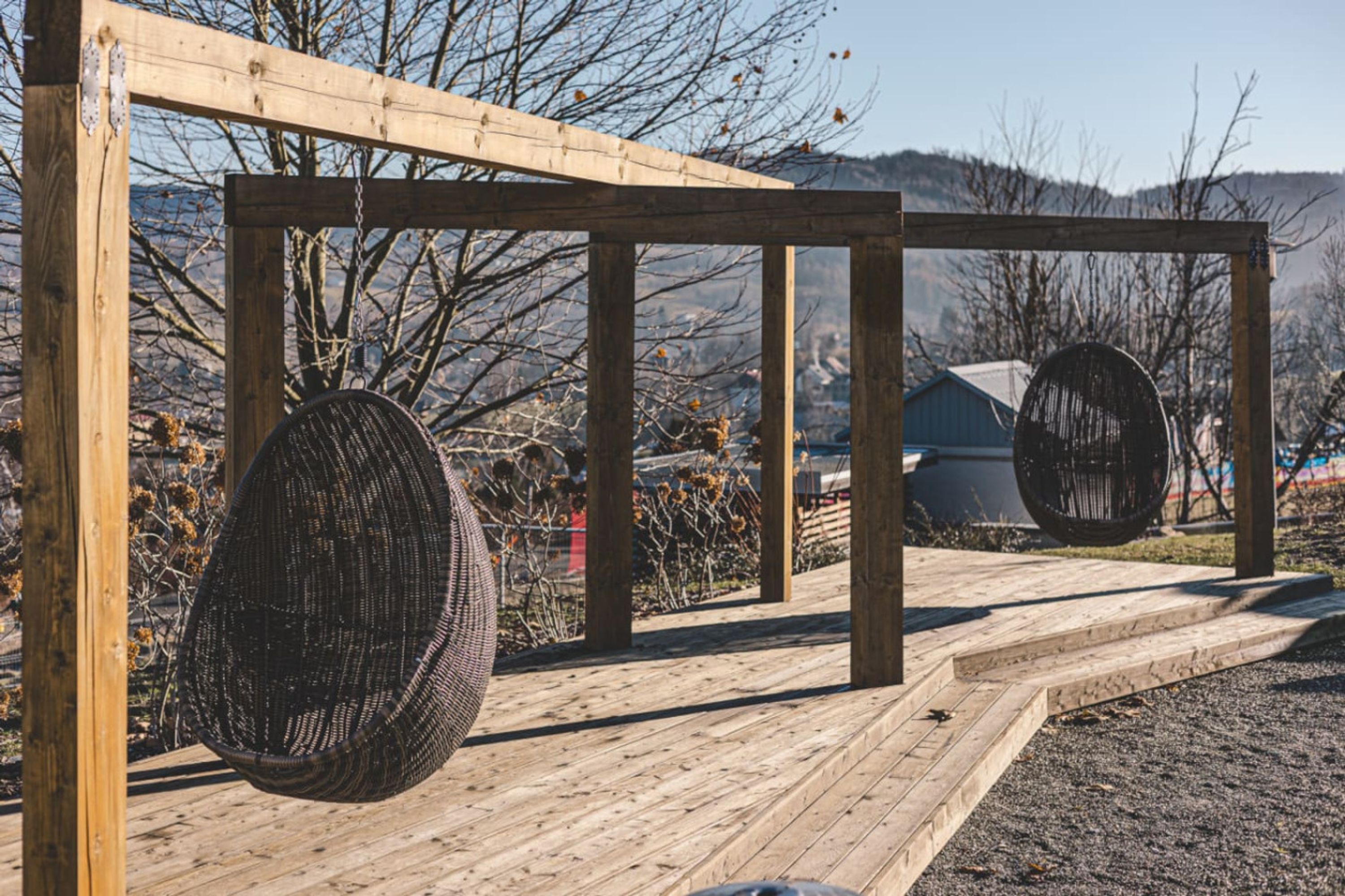 Una estructura de pérgola de madera con dos sillas colgantes esféricas.