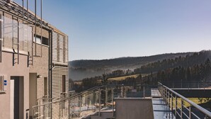 Ein modernes Gebäude mit Glasfassade, einer Metalltreppe und Blick auf eine hügelige Landschaft.
