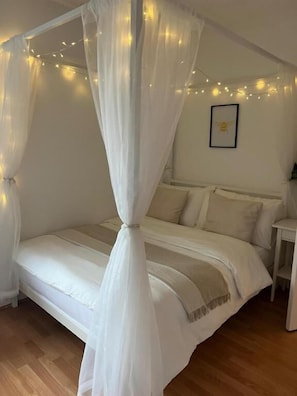 A bedroom with a canopy bed, bedside tables, and a framed picture on the wall. - The Cotton Mill Hideaway (Manchester)