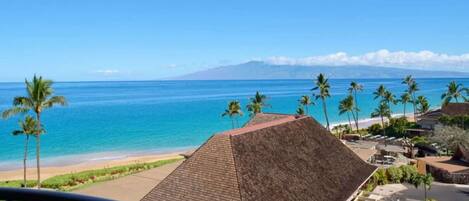 A beachfront property with a clear view of the ocean and a mountain in the distance.
