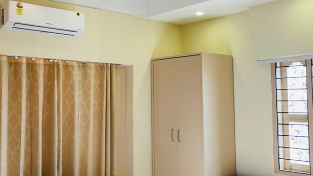 Una habitación de hotel con cama, escritorio, armario y ventilador de techo.