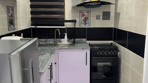 A compact kitchen with a built-in oven, a sink, and a refrigerator. - RBZ Apartments (Lagos)