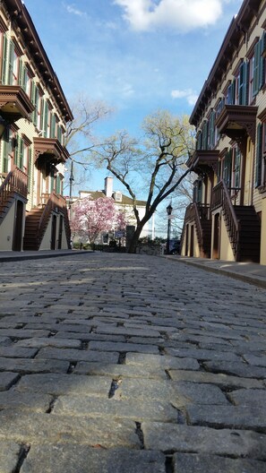 Eine gepflasterte Straße, gesäumt von historischen Gebäuden mit grünen Fensterläden und aufwendigen Balkonen.