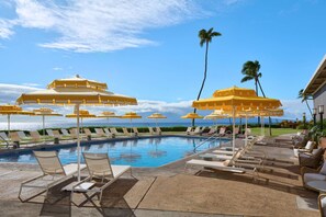 A poolside area with sun umbrellas, lounge chairs, and a view of the ocean. - Whalers Village Access + Pool. Dining. Gym. (Lahaina)