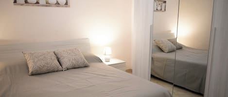 Un dormitorio con cama, mesita de noche y espejo.