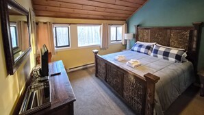 Une chambre à coucher avec un plafond en bois, un lit avec un oreiller à carreaux, une table de chevet et une fenêtre avec des rideaux.