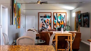 A dining area with a table, chairs, and abstract art on the walls. - Mystic Breeze Suite 1 (Tarpon Springs)