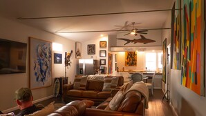 A living room with a sofa, a ceiling fan, and a kitchen area in the background. - Mystic Breeze Suite 1 (Tarpon Springs)