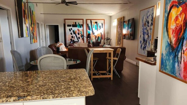 A modern kitchen with granite countertops, white cabinetry, and a dining area with a wooden table and chairs. - Mystic Breeze Suite 1 (Tarpon Springs)