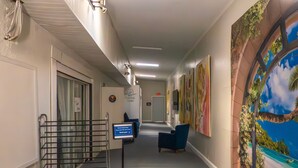A hallway with a reception desk, a blue chair, and a wall with a tropical mural. - Mystic Breeze Suite 1 (Tarpon Springs)
