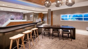 A modern hotel lobby with a reception desk, bar stools, a dining area with a large table and chairs, and a large window with a view. - Near Downtown Parker | Free Breakfast + Pool (Parker)