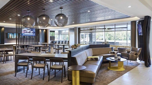 A modern hotel lobby with a bar area, seating arrangements, and large windows providing natural light. - Near Downtown Parker | Free Breakfast + Pool (Parker)