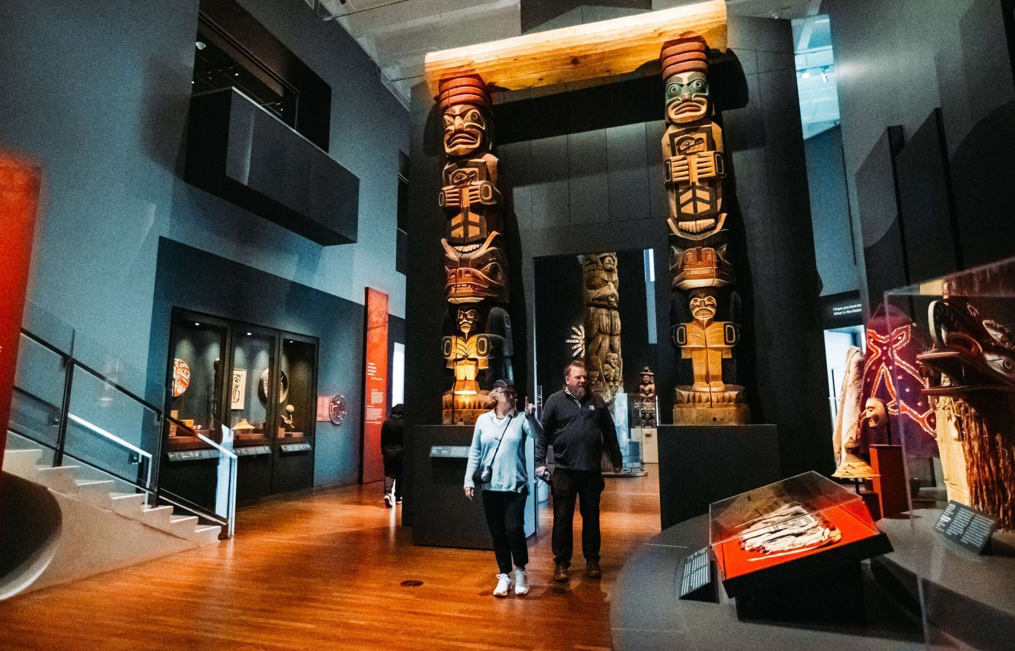 Un interior moderno con pisos de madera, una escalera y una exhibición de totems.