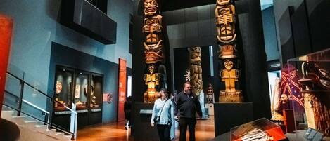 Un interior moderno con pisos de madera, una escalera y una exhibición de totems.