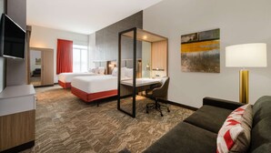 A hotel room with two beds, a desk, a TV, a sofa, a mirror, and a painting on the wall. - Easy Denver Access | Indoor Pool + Free Parking (Parker)