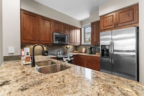 A modern kitchen with granite countertops, stainless steel appliances, wooden cabinets, and a large window. - Lakefront Condo Near the Slopes - Walk to Shops & Dining (Keystone)