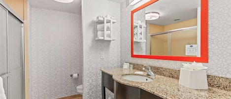 Ein Badezimmer mit Waschbecken, Spiegel, Seifenspender und Toilette.