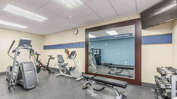 A gym with cardio machines, a bench, and free weights.