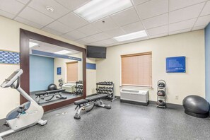 Un gimnasio con equipo de ejercicio, un espejo y un letrero en la pared.