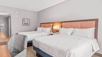 A hotel room with two beds, a desk, and a chair.