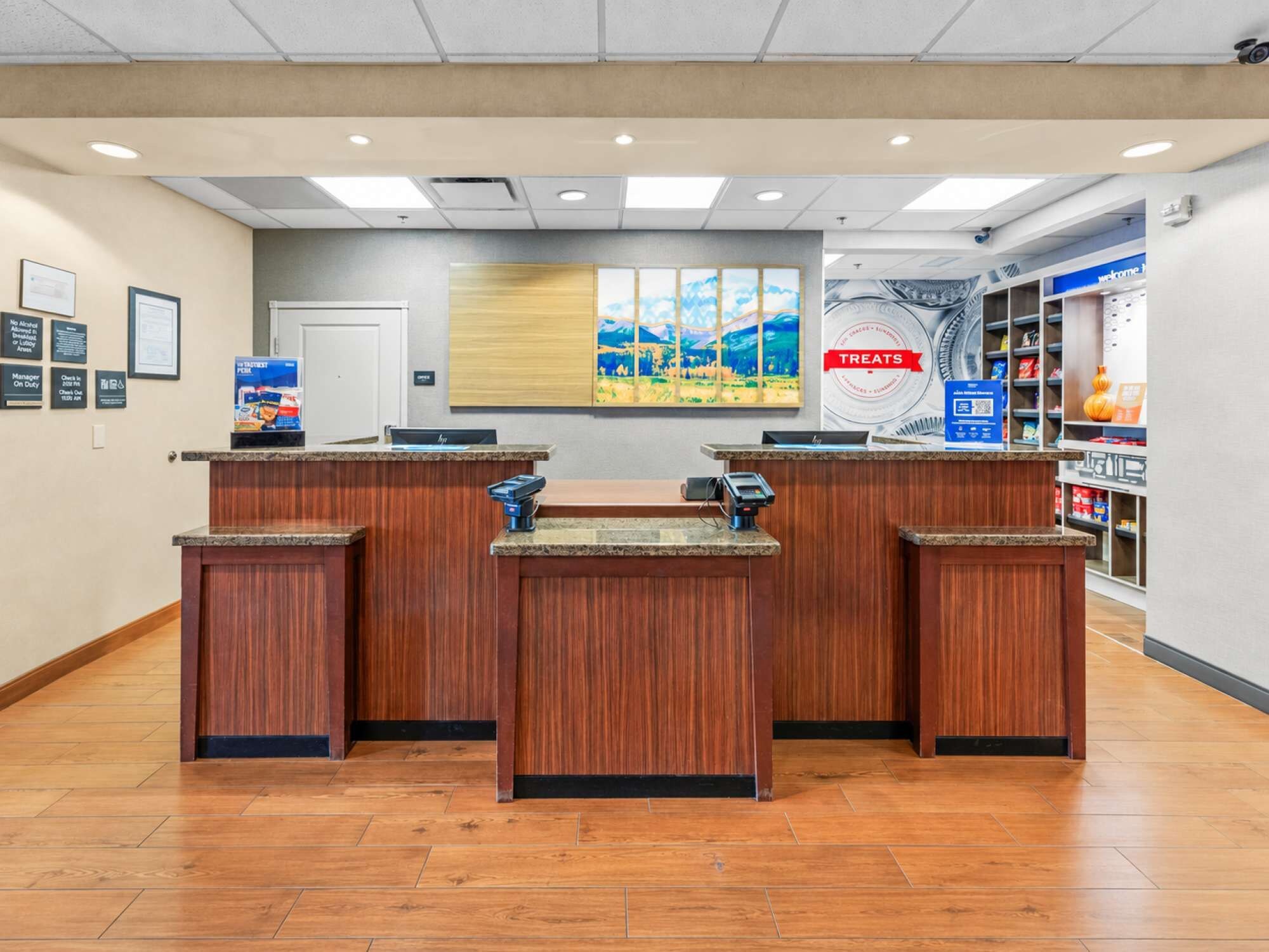 A reception area with wooden counters, a painting on the wall, and a 'Treats' sign.