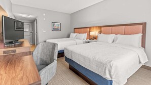 A hotel room with two beds, a TV, a desk, and a chair.