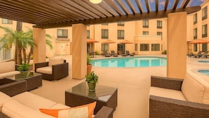 A poolside area with lounge chairs, a pool, and a covered patio with seating. - Steps to the Beach | Pool, Gym & Free Breakfast (Carlsbad)