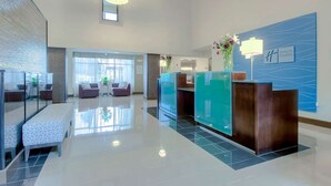 A modern hotel lobby with a reception desk, seating area, and a large window providing natural light. - Steps to the Beach | Pool, Gym & Free Breakfast (Carlsbad)