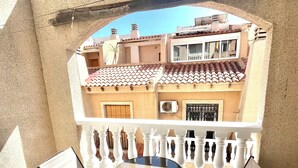 A balcony with a table and chairs, a view of neighboring buildings, and a white railing. - 2BR Apartment Center of Torrevieja (Torrevieja)