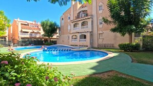 A pool surrounded by a well-maintained lawn and a building with balconies. - 2BR Apartment Center of Torrevieja (Torrevieja)
