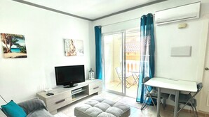 A living room with a sofa, a television, a small table, and a balcony with a view. - 2BR Apartment Center of Torrevieja (Torrevieja)