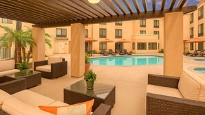 A poolside area with lounge chairs, a pool, and a covered patio with seating.