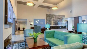 A spacious lobby with a green sofa, a wooden coffee table, and a large abstract wall art piece.