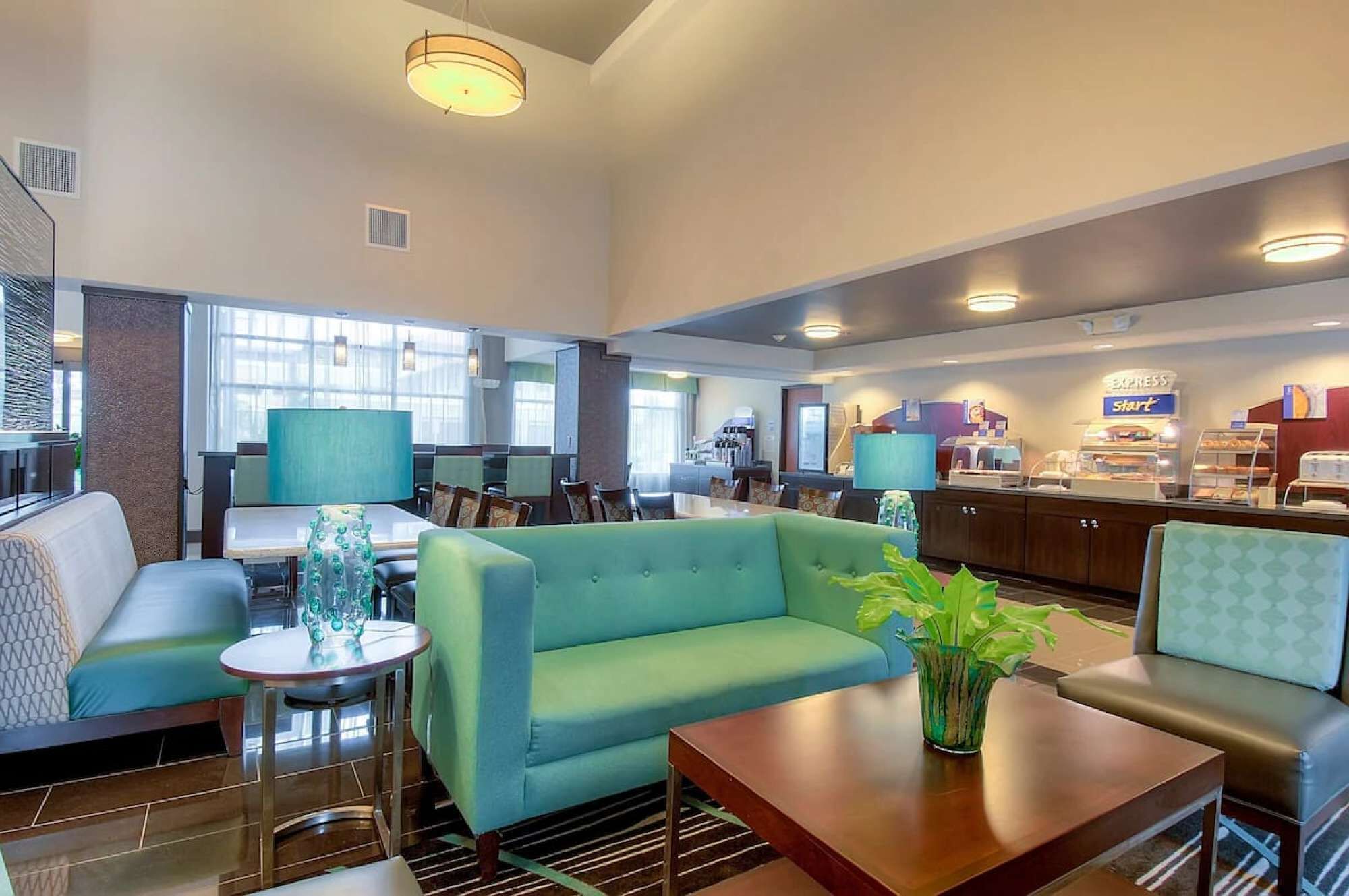 A hotel lobby with seating areas, a coffee station, and a reception desk.