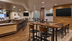 Un restaurant moderne doté d’un bar, de plusieurs espaces pour s’asseoir et d’un grand écran mural.