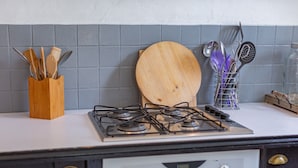 Une cuisine équipée d’une cuisinière à gaz, d’une planche à découper en bois et d’un porte-ustensiles.