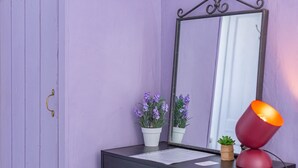 Une commode avec un miroir, deux plantes en pot et une lampe rouge.