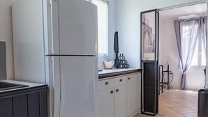 A kitchen with a white refrigerator, wooden cabinets, and a window.