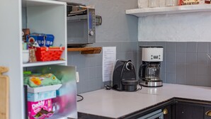 Una cocina con cafetera, hervidor y diferentes alimentos sobre la encimera.