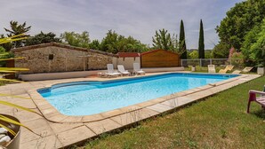 A rectangular swimming pool with a stone border, surrounded by grass and trees. There are lounge chairs and a small building with a red roof. - “Les Nougats” Room with Private Terrace, Shared Garden, and Wi-Fi (Portes-en-Valdaine)