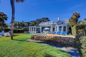 A large house with a swimming pool, a covered patio, and a stone wall. - Amazing Oceanfront estate (Hilton Head)