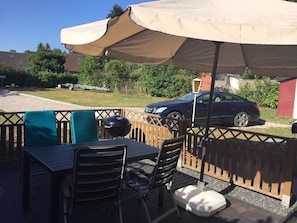 Une terrasse extérieure avec une table, des chaises et un grand parasol.