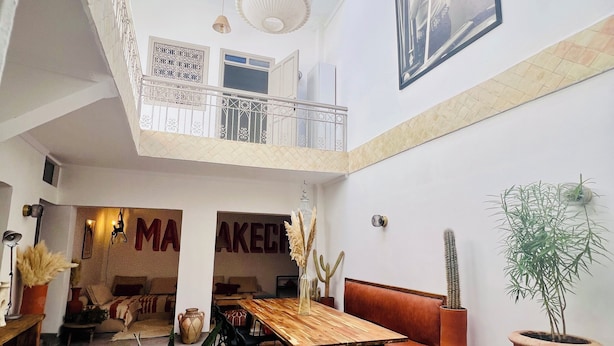 Un interior espacioso con techo alto, piscina central y comedor con mesa y sillas de madera.
