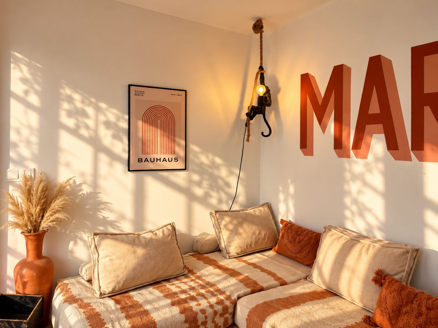 Une pièce chaleureuse, avec un canapé, une affiche du Bauhaus encadrée et un luminaire fixé au mur.