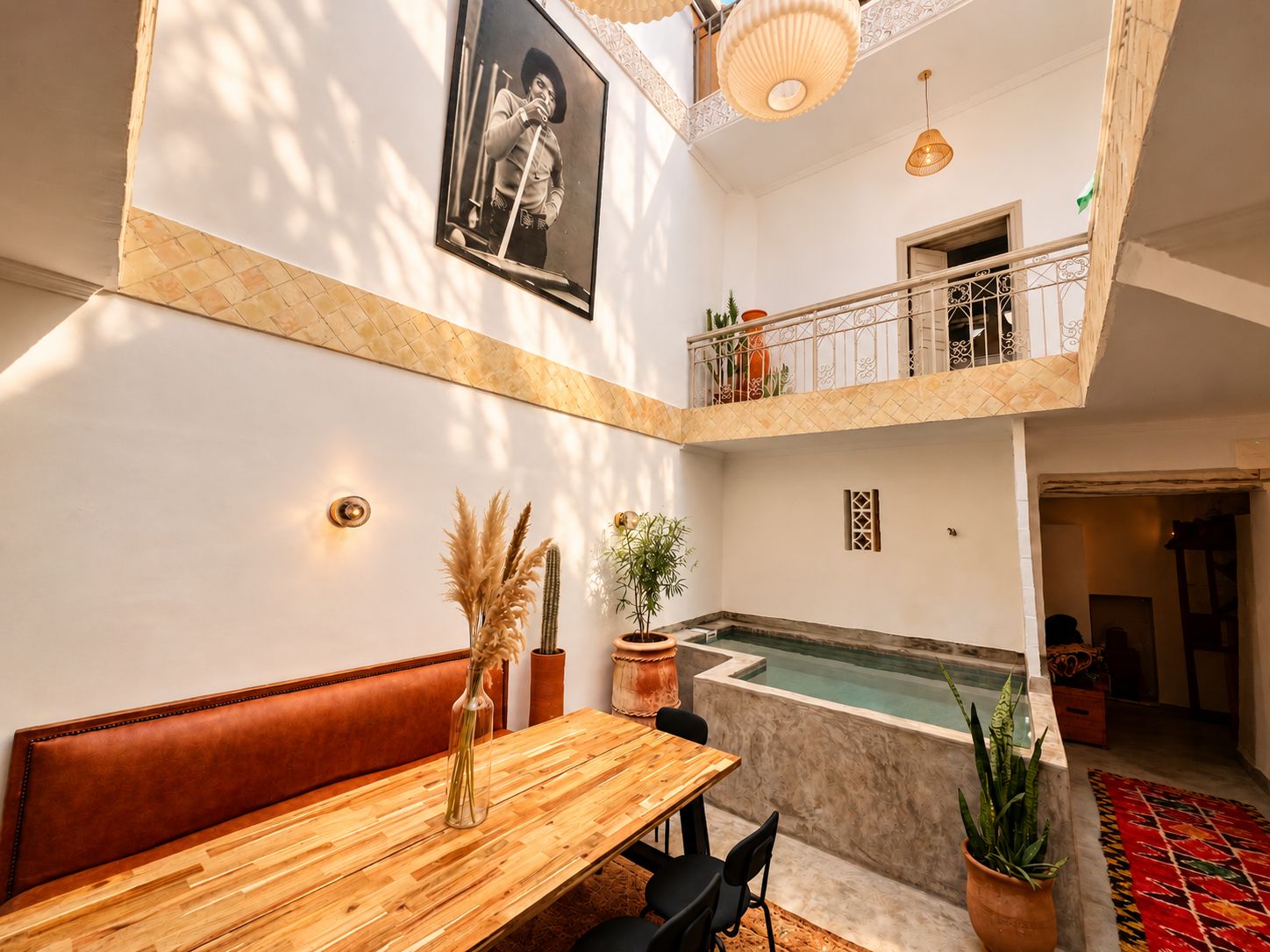 A spacious interior with a wooden dining table, a bench, a small pool, and a balcony with plants.