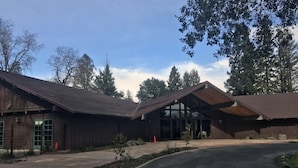 A large building with a modern architectural design, featuring a prominent entrance with glass doors and a covered area. - Near Lake Mendocino + Free Breakfast. Pool. (Ukiah)
