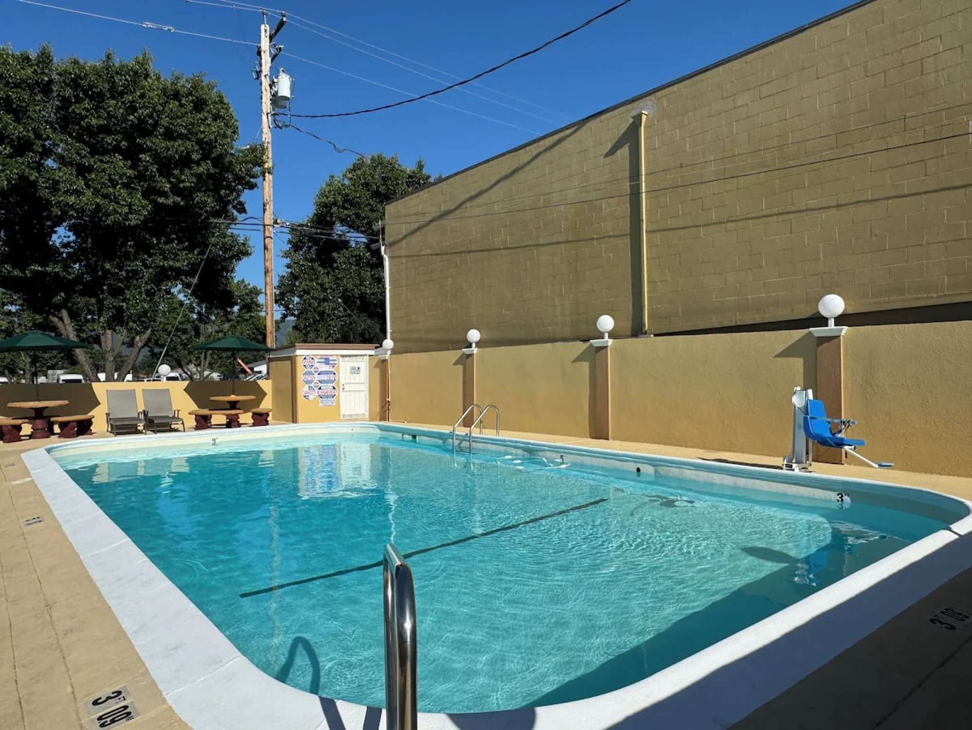 Pool with chairs and fence along the yellow wall