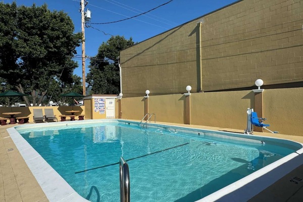 Pool with chairs and fence along the yellow wall