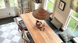 A dining area with a wooden table, wicker chair, and a bowl of fruit. - Gorgeous Hudson Valley Farmhouse On 14 Acres 3 Bedroom Home (Old Chatham)